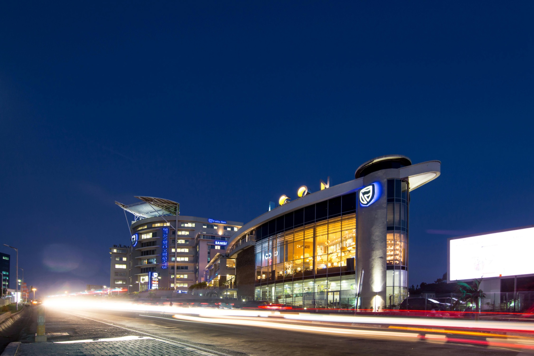 Commercial buildings lit at night along a city road