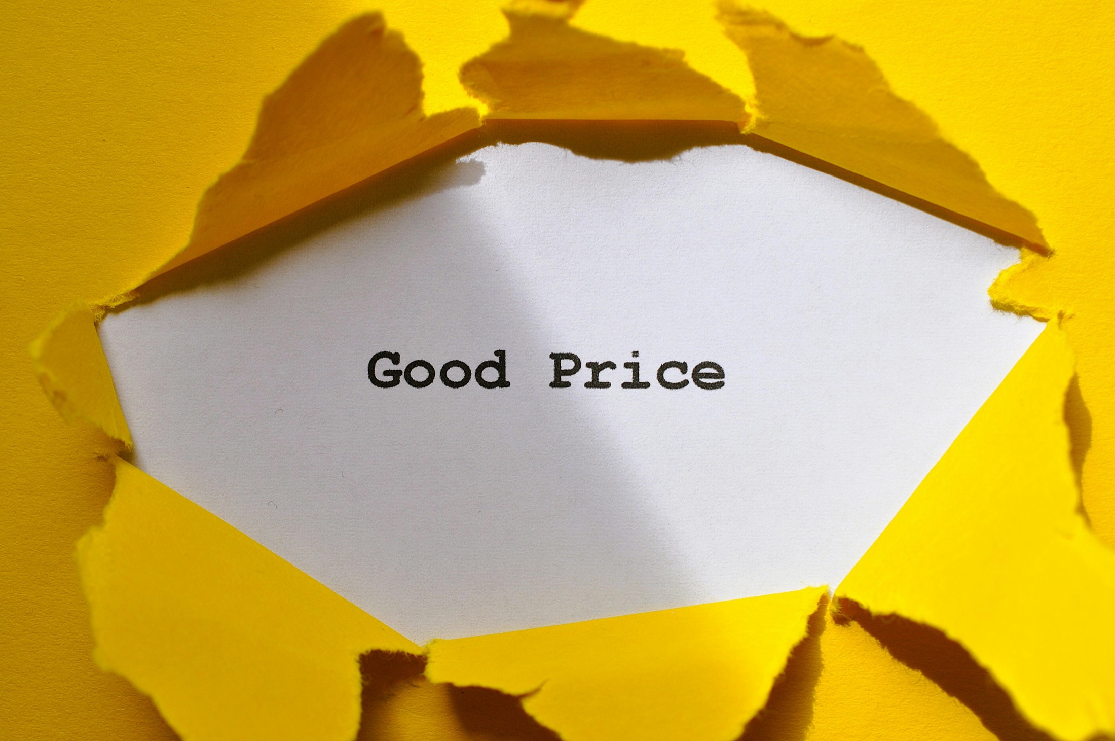 A torn yellow paper surface revealing the words Good Price