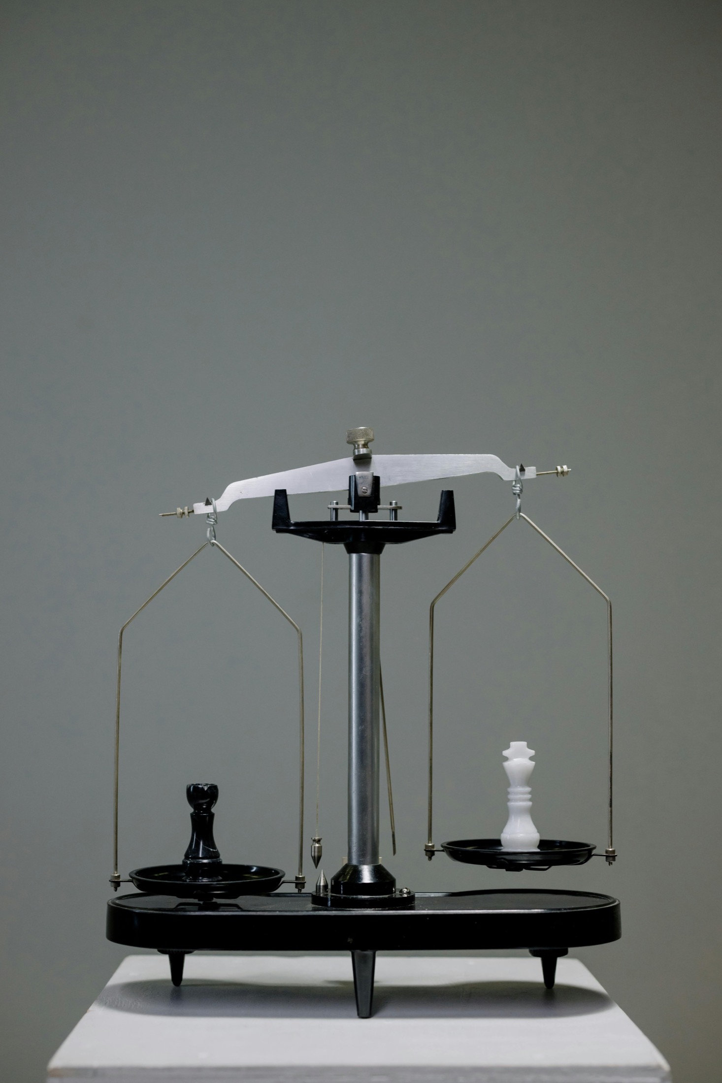 A balance scale with black and white chess pieces